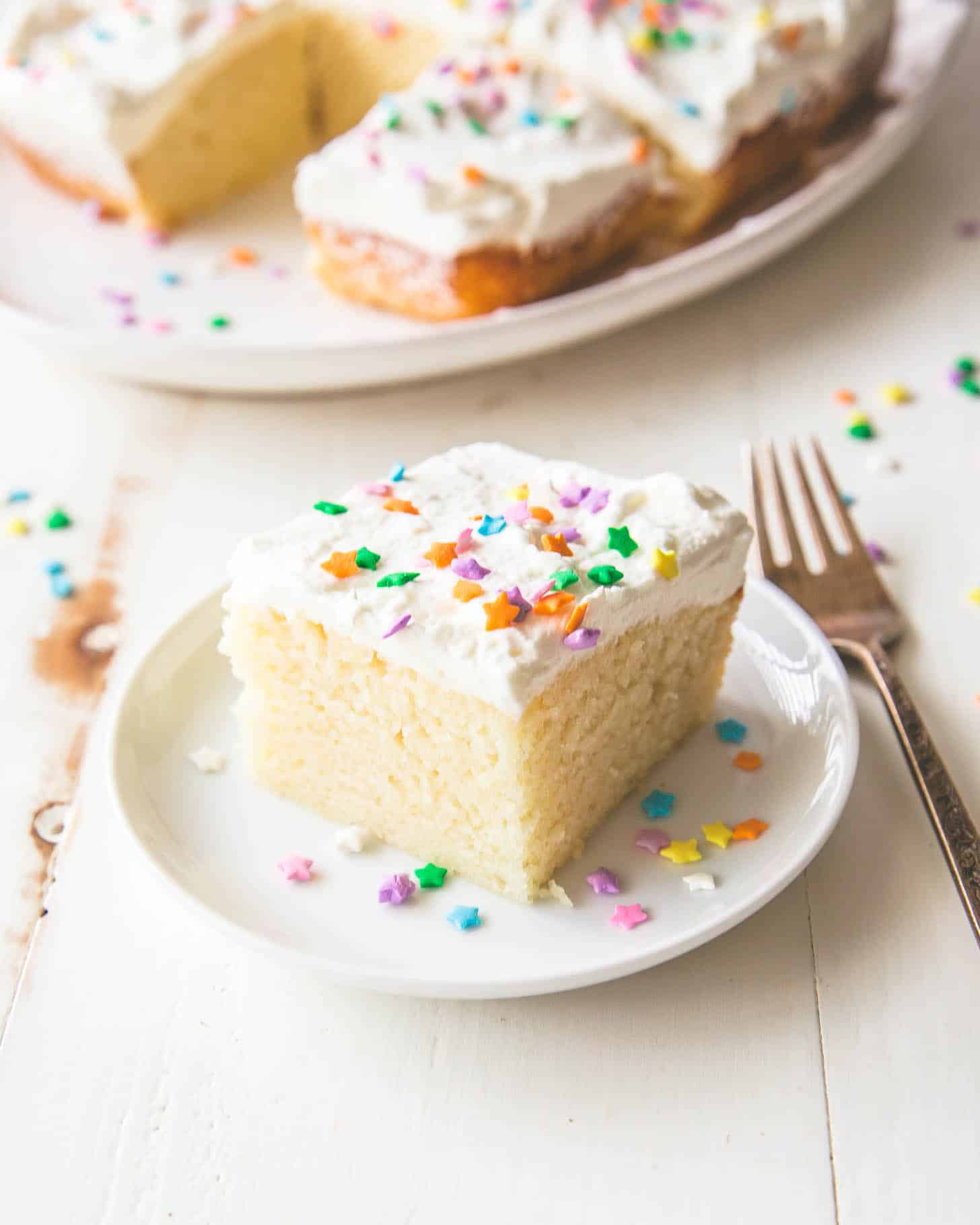  a piece of frosted vanilla snack cake on a white plate