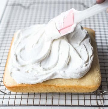 spreading vanilla frosting on a sheet cake