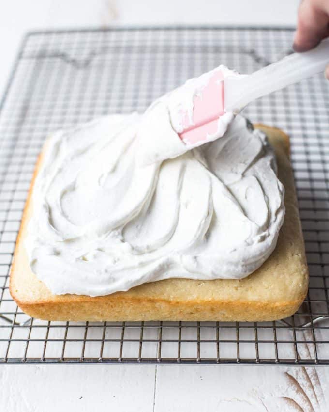 spreading vanilla frosting on a sheet cake