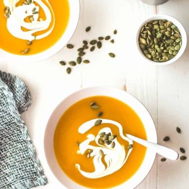 two bowls of butternut squash soup on a table