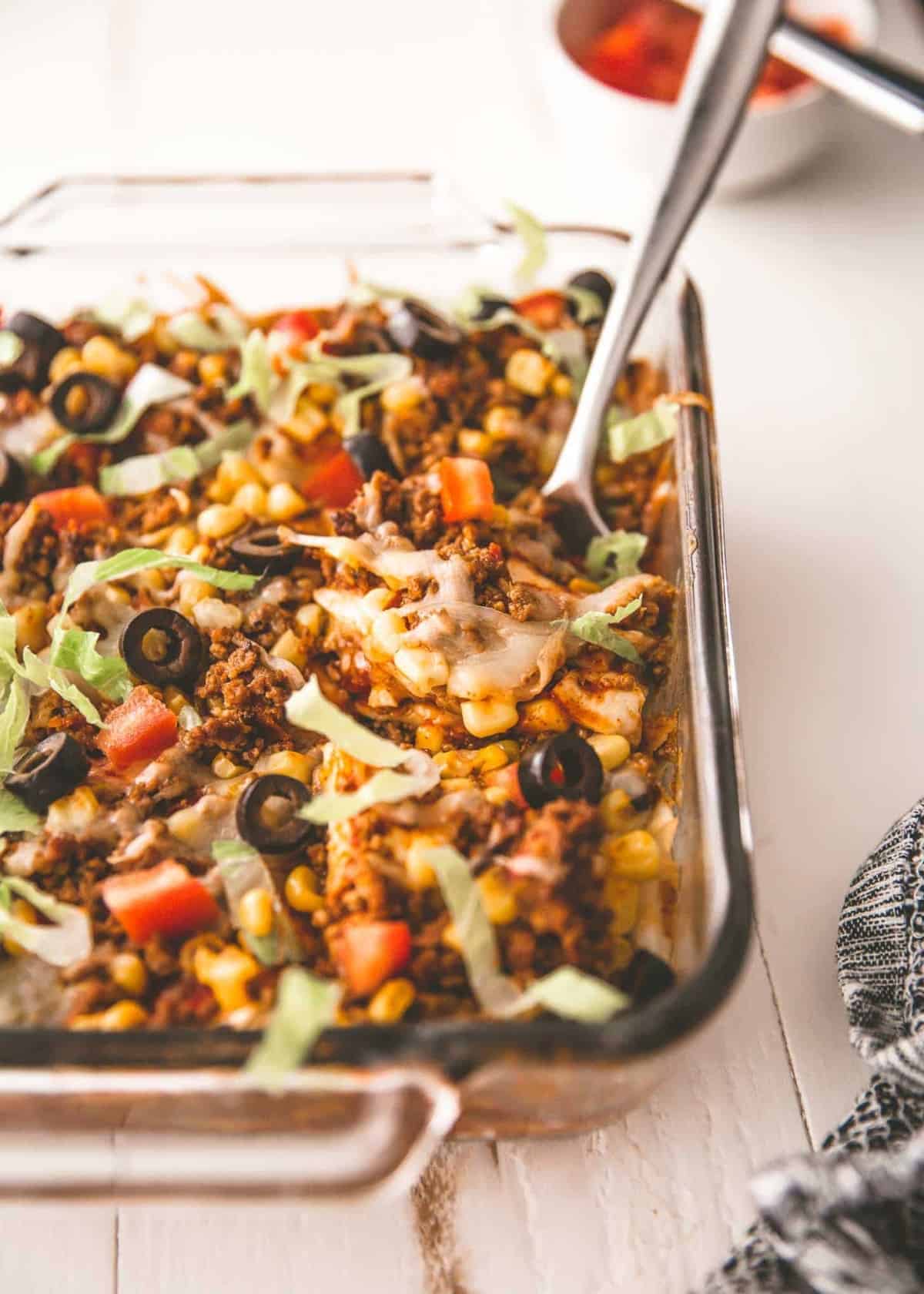 taco casserole in a clear baking dish with a spoon