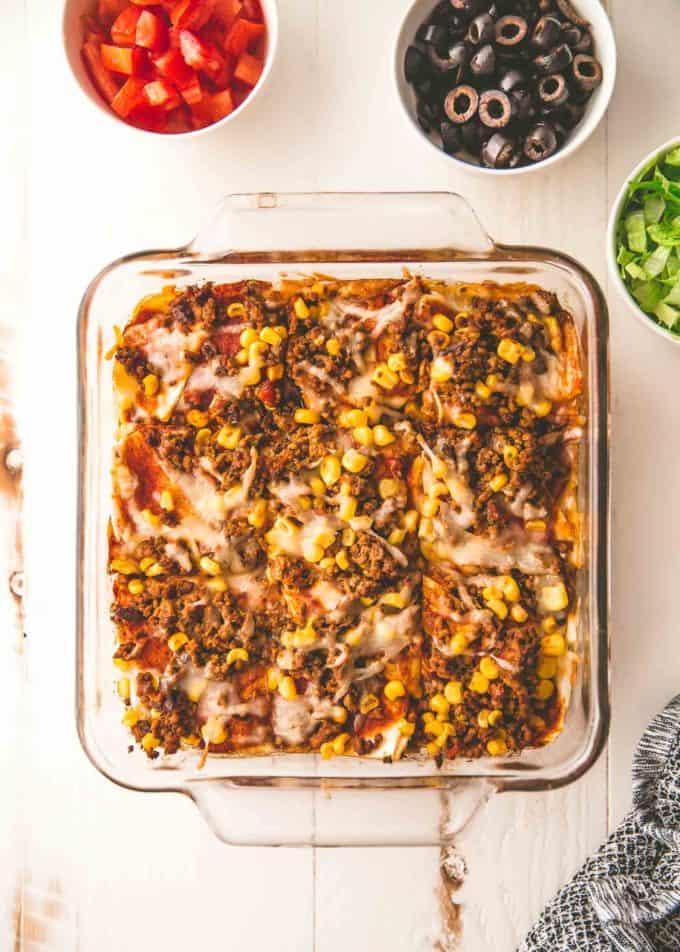 taco casserole in a clear baking dish on a white table
