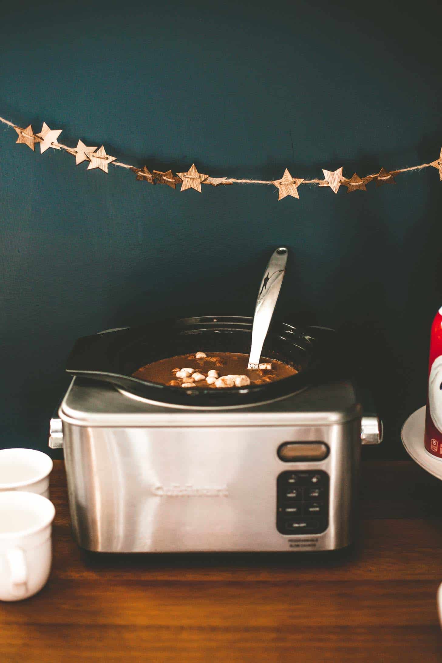 slow cooker with hot chocolate on a wooden bench