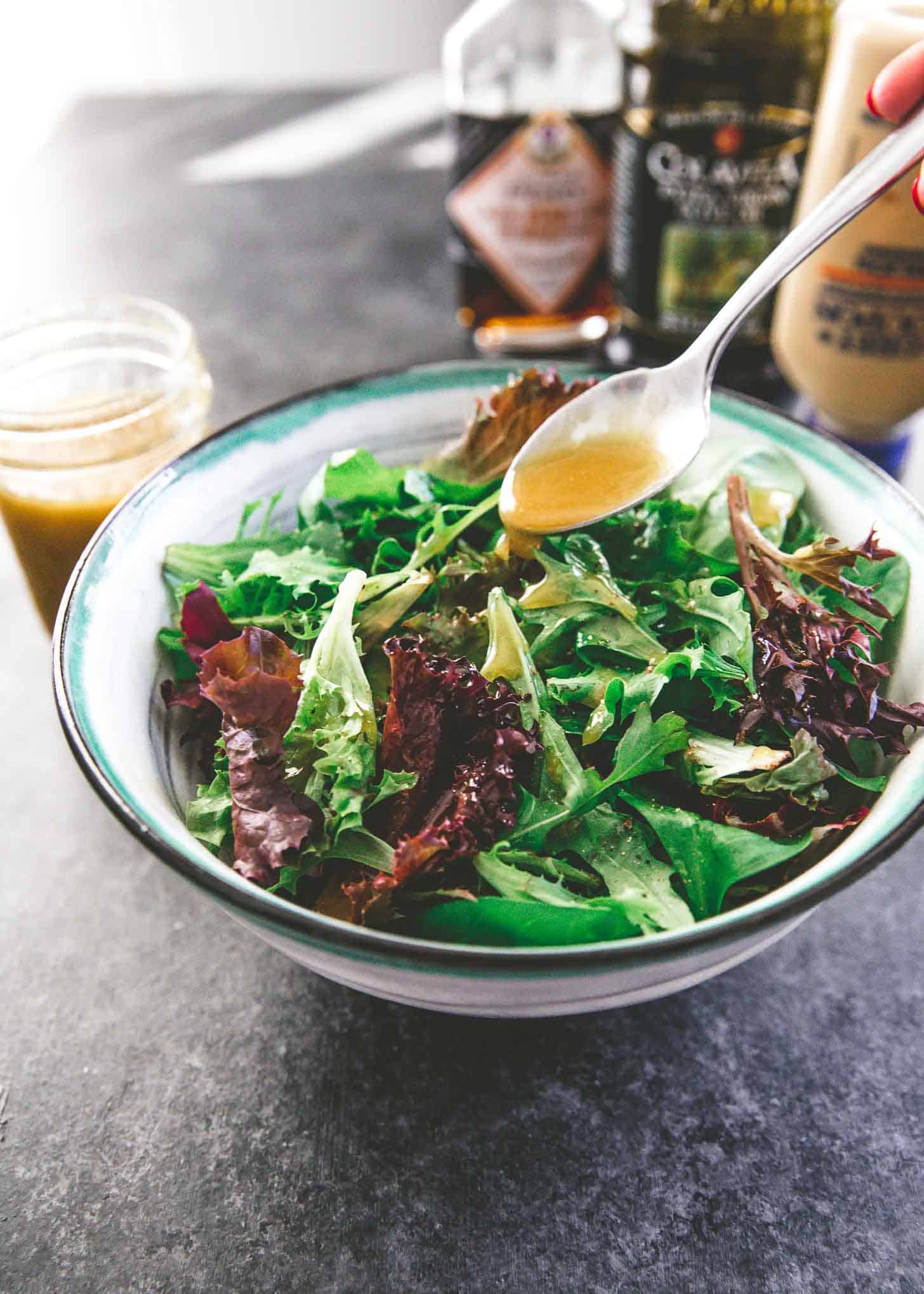 adding vinaigrette to salad