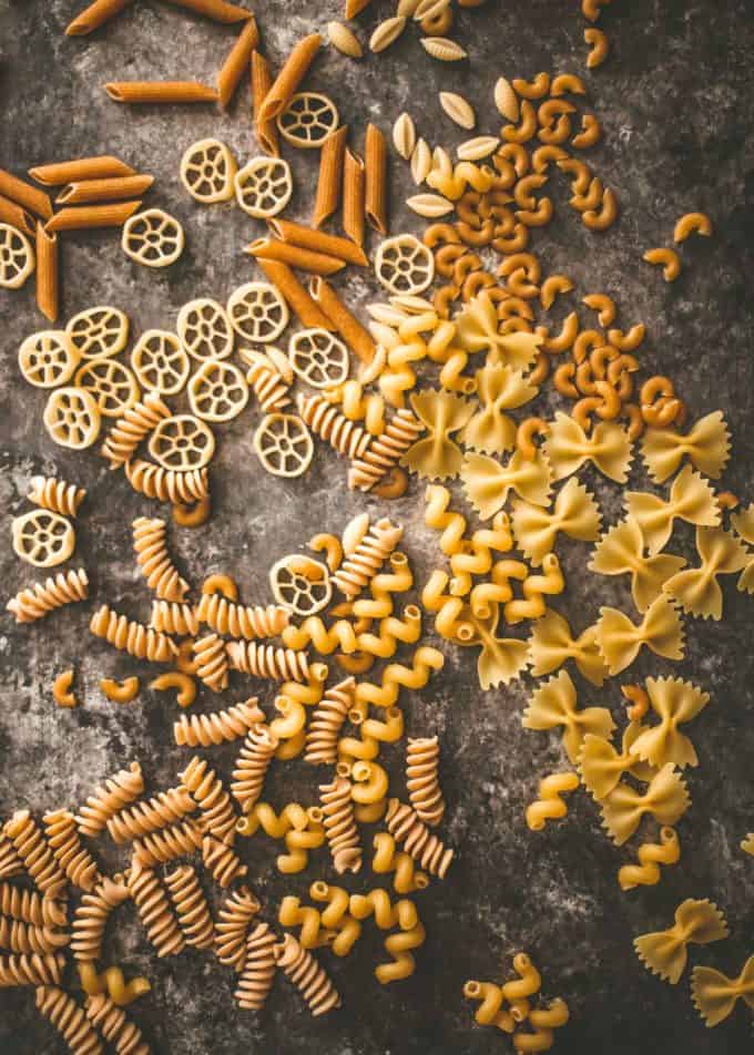 different types of raw pasta on a gray countertop
