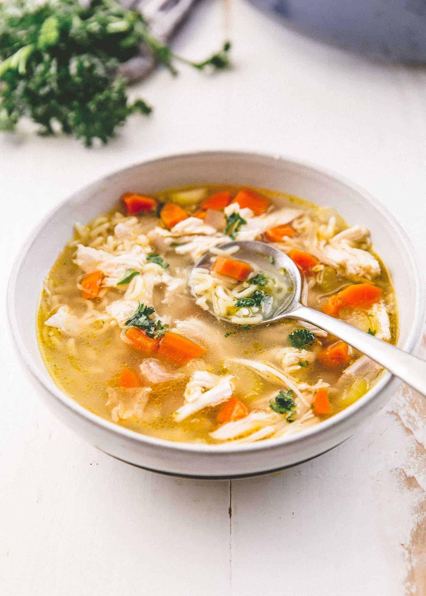 a spoon in a bowl of chicken noodle soup with miso