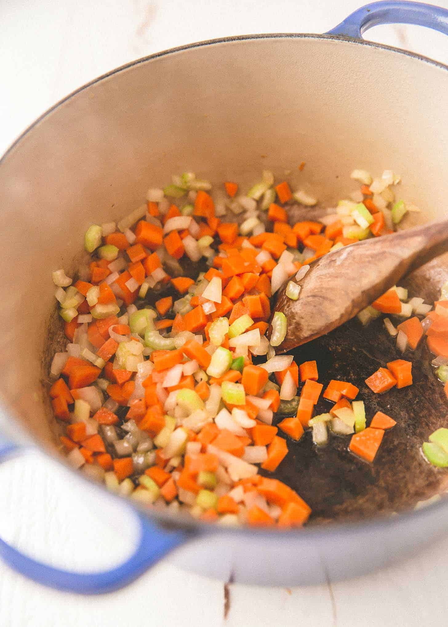 stirring carrots, onions and celery in a dutch oven