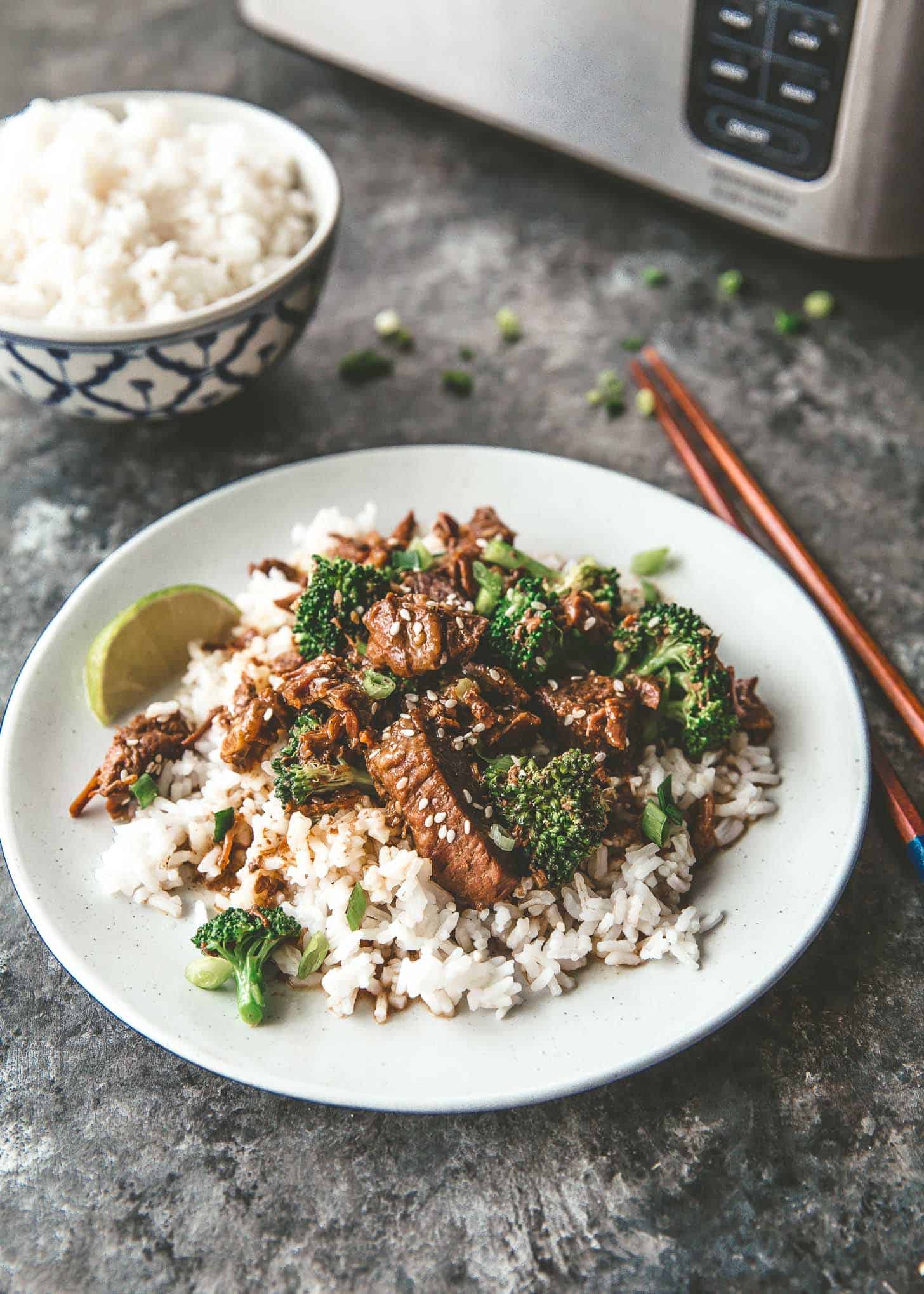 beef and broccoli over rice on a white plate