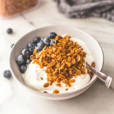 slow cooker granola over yogurt in a white bowl