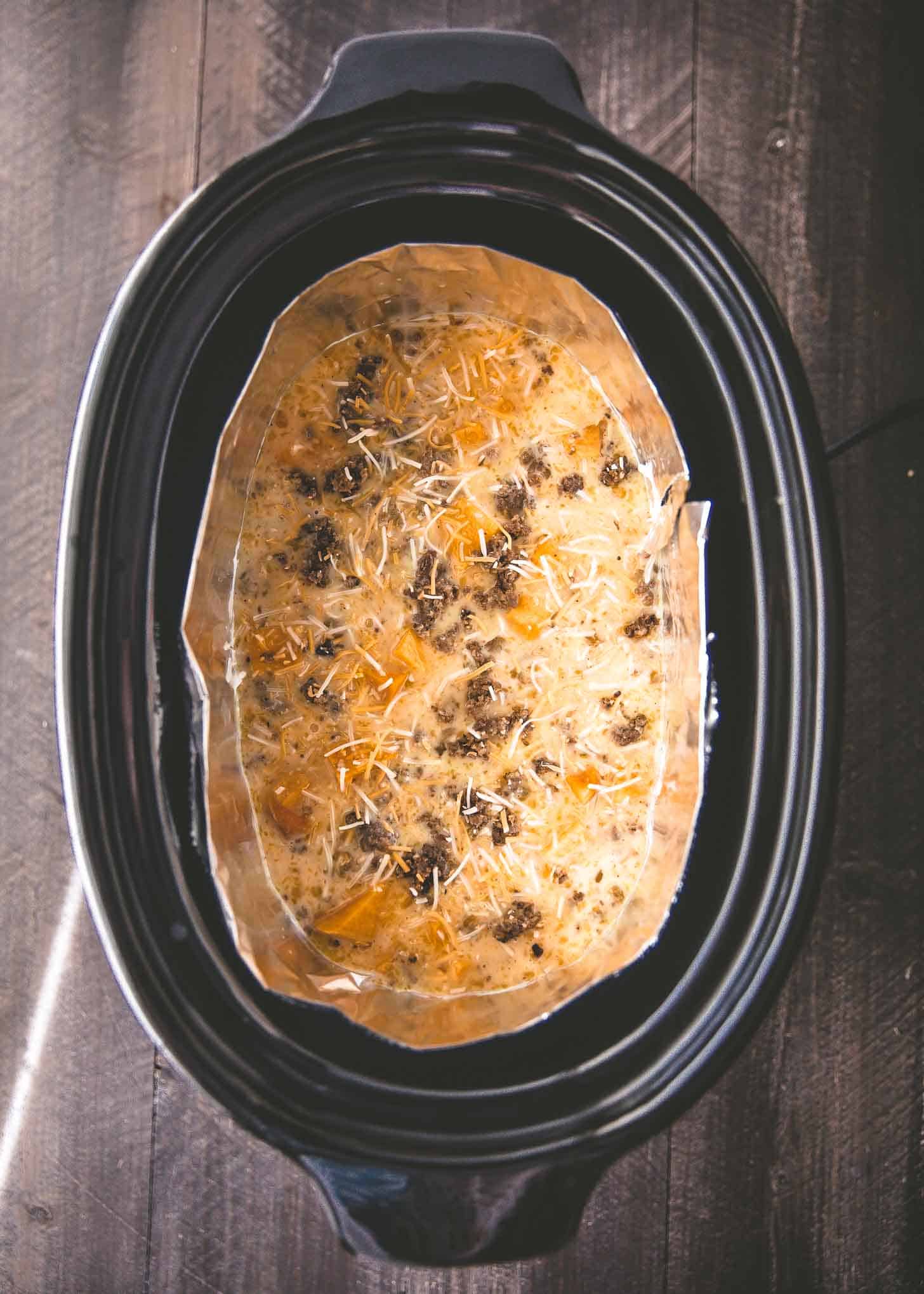 overhead image of uncooked breakfast casserole in a slow cooker
