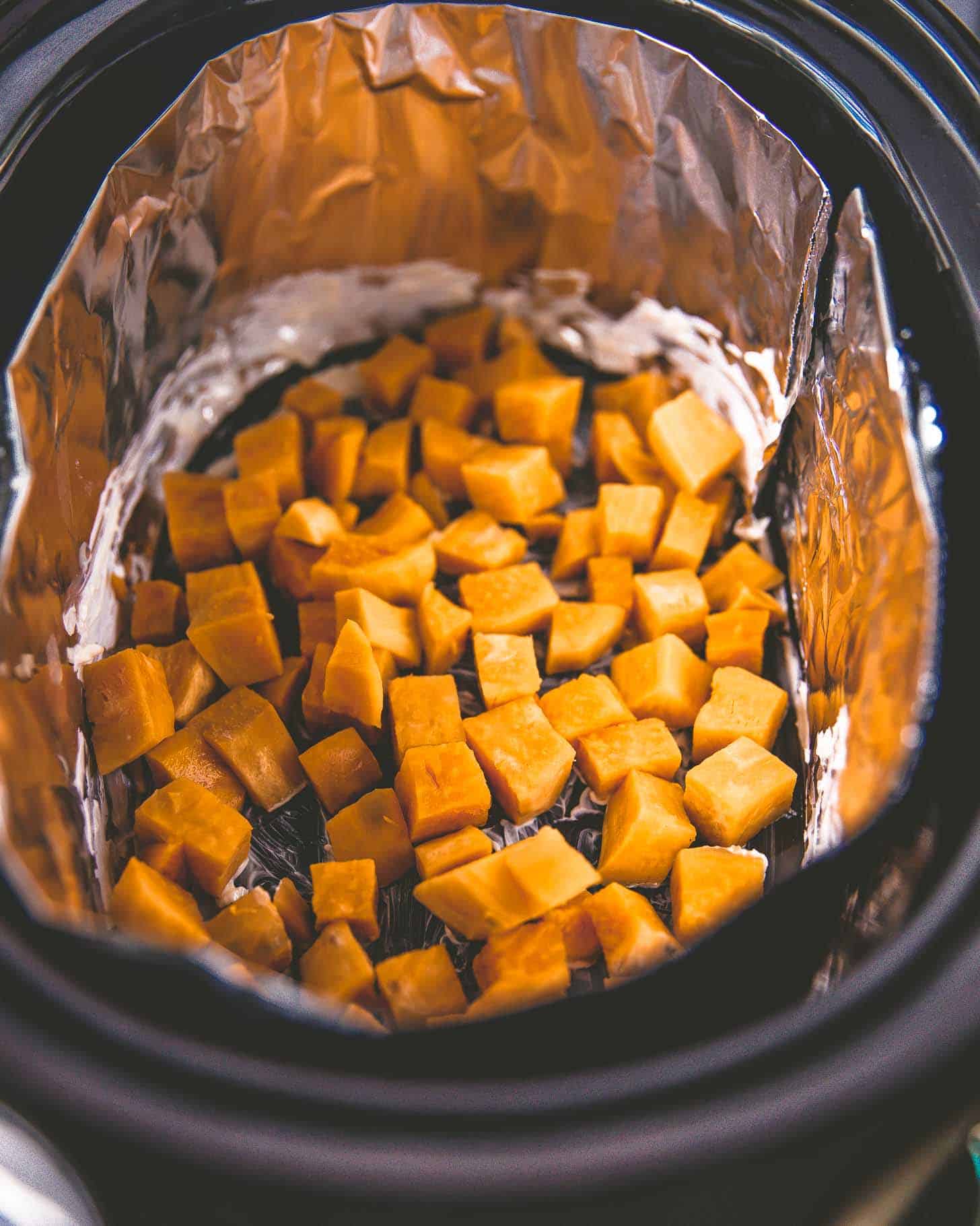overhead image of cut sweet potatoes in the slow cooker