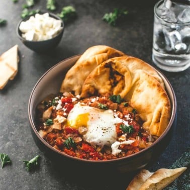 slow cooker shakshuka in a black bowl with naan bread
