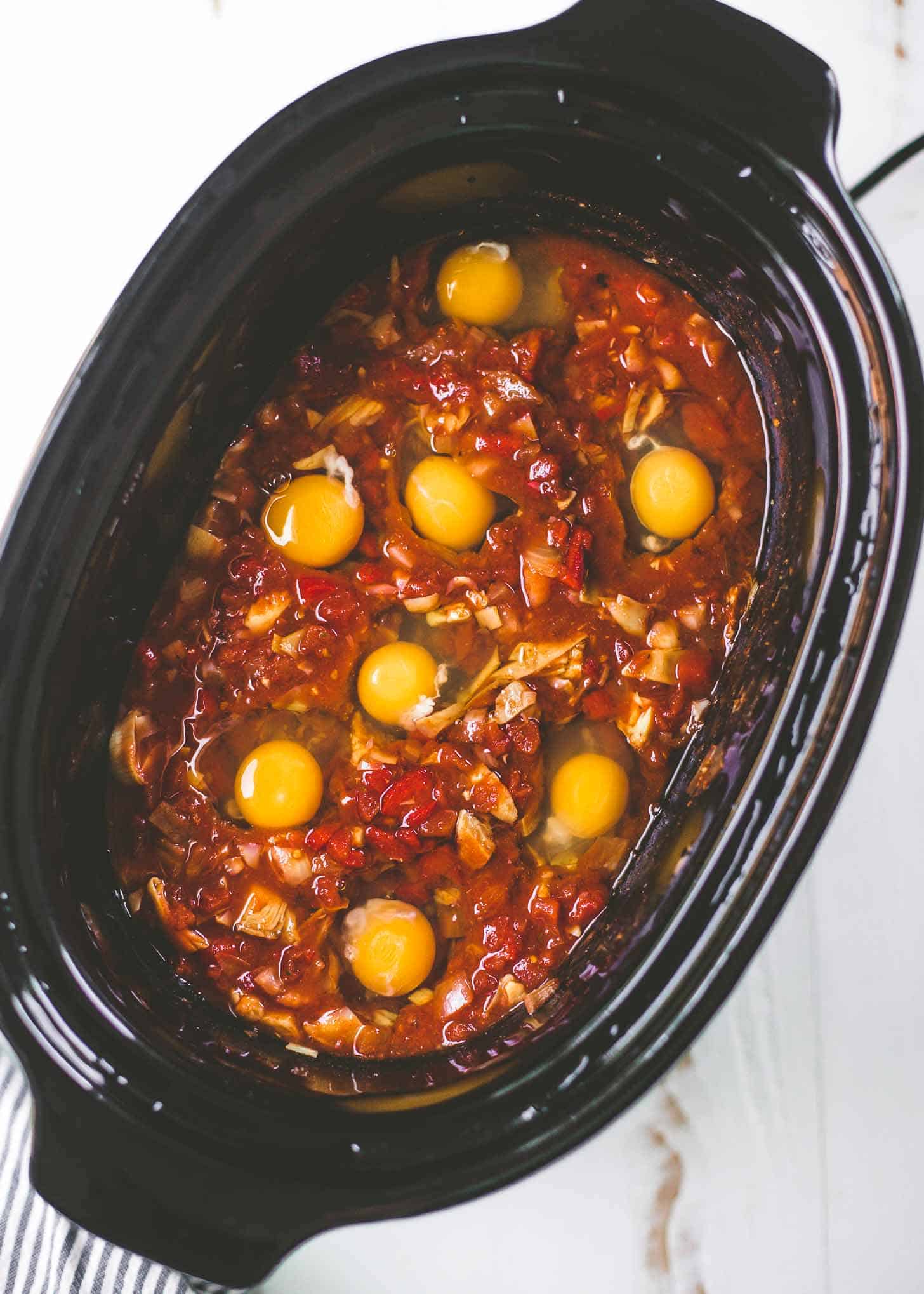 overhead image of uncooked slow cooker shakshuka with eggs