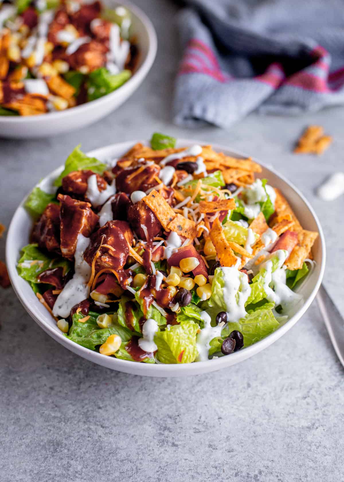 romaine lettuce salad topped with corn, black beans, tortilla strips, and bbq chicken