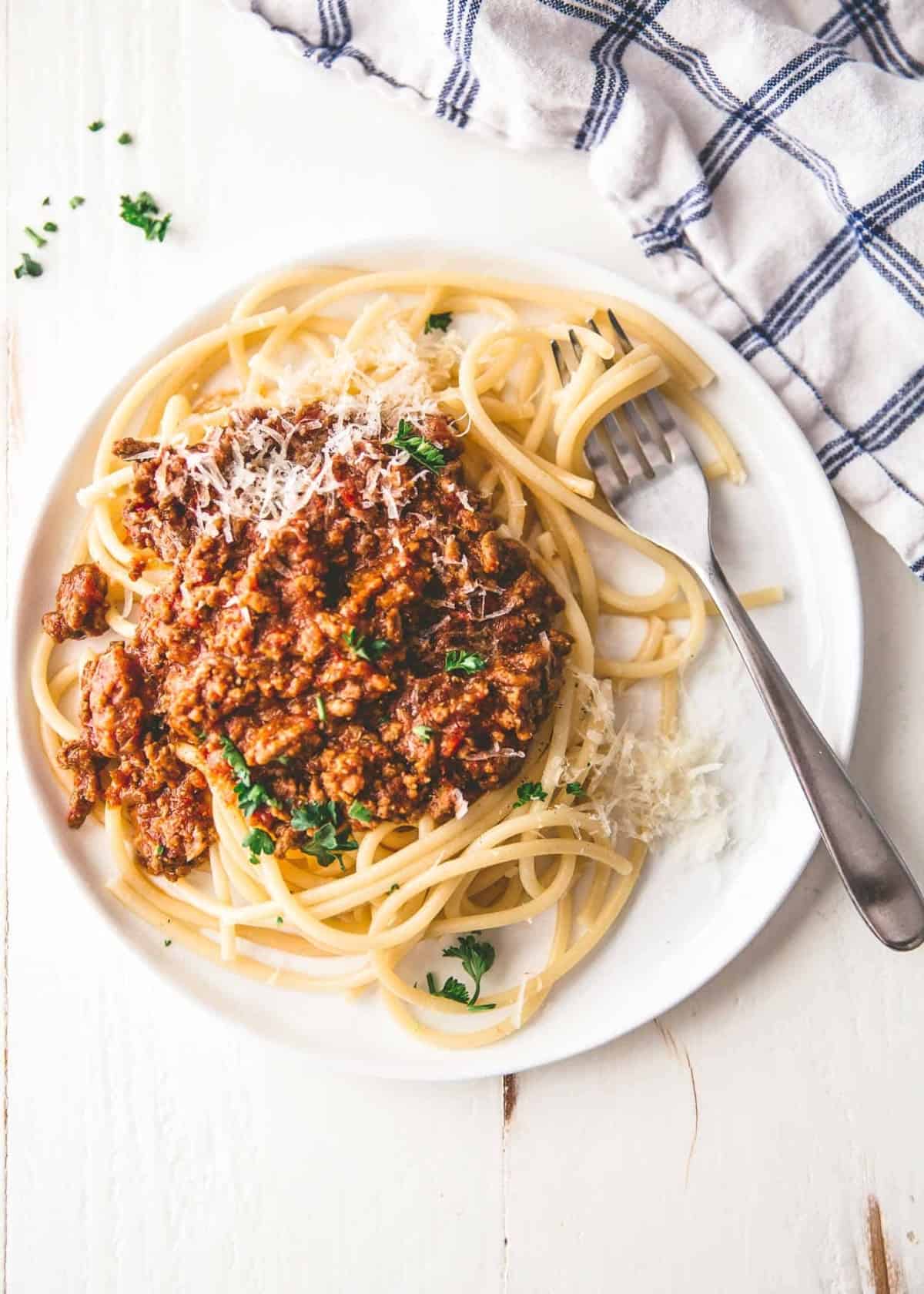 classic beef ragu over pasta on a white plate
