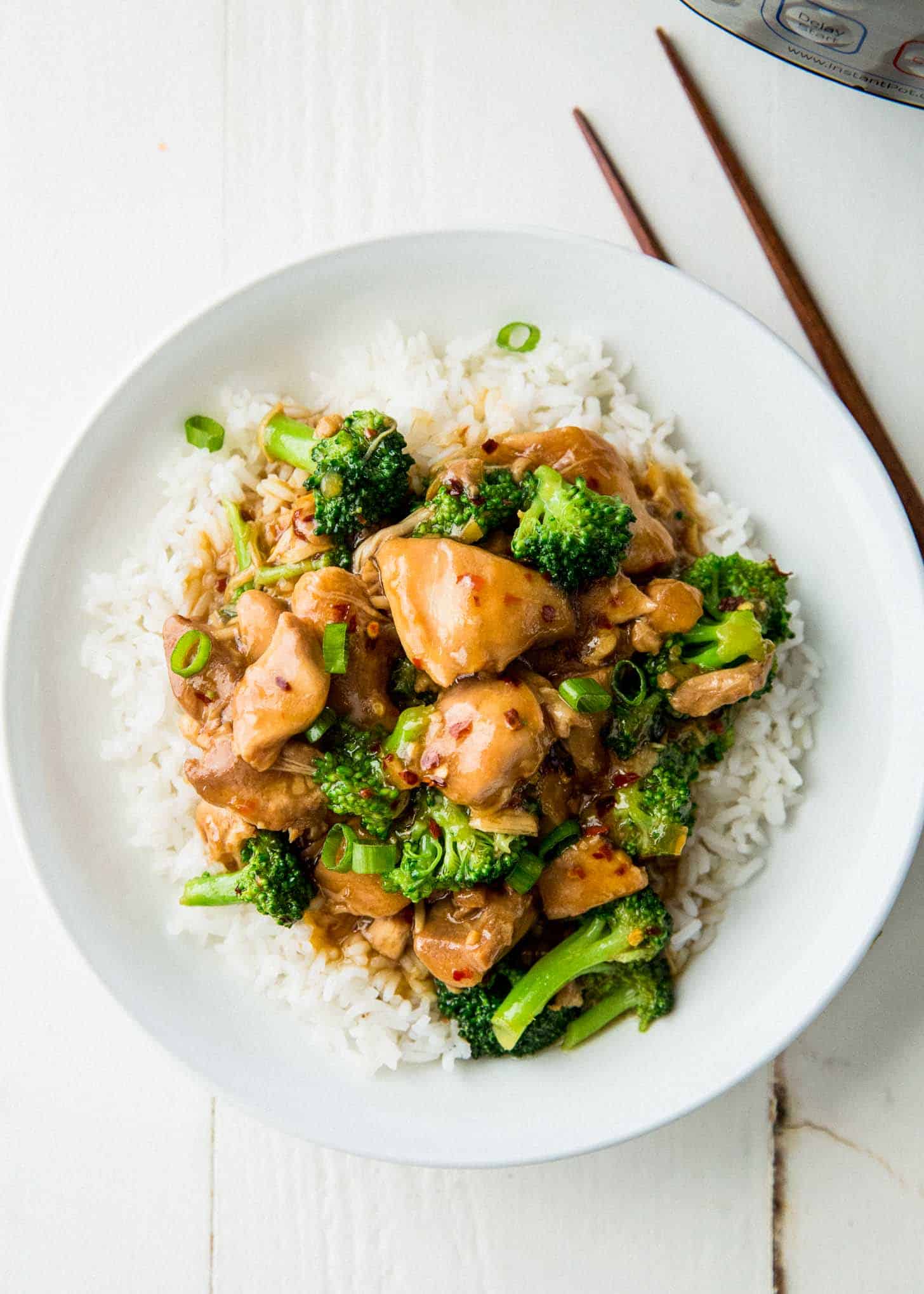 overhead image of general tso's chicken over rice in a white bowl