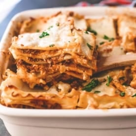 a slice of Lasagna Bolognese in a white baking dish