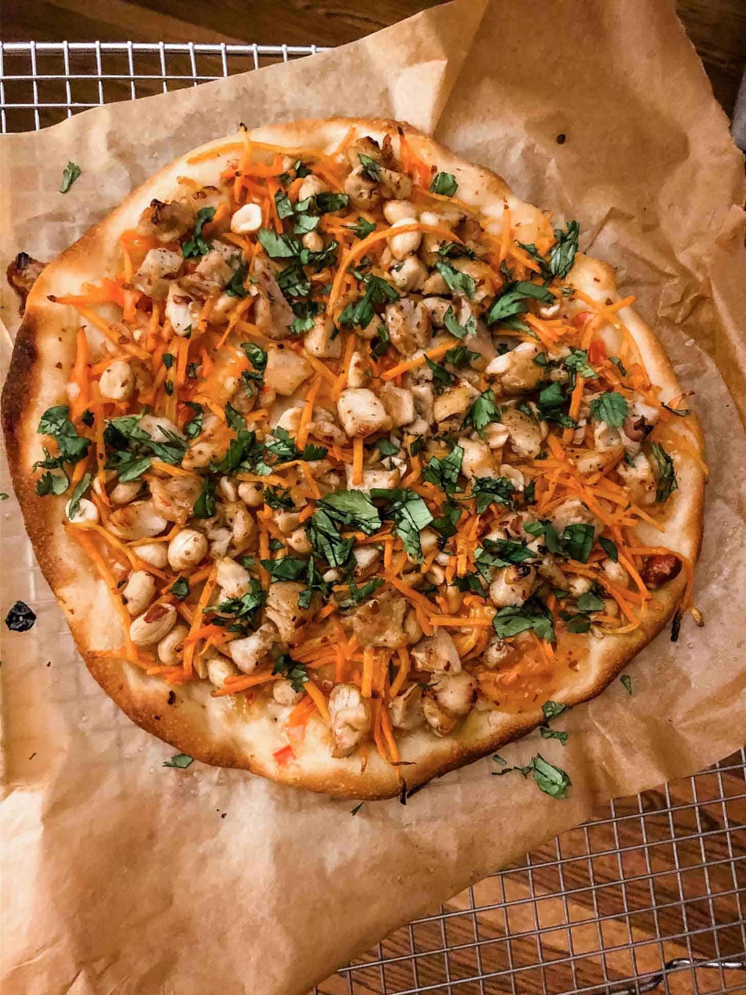 Thai chicken pizza on a piece of parchment paper