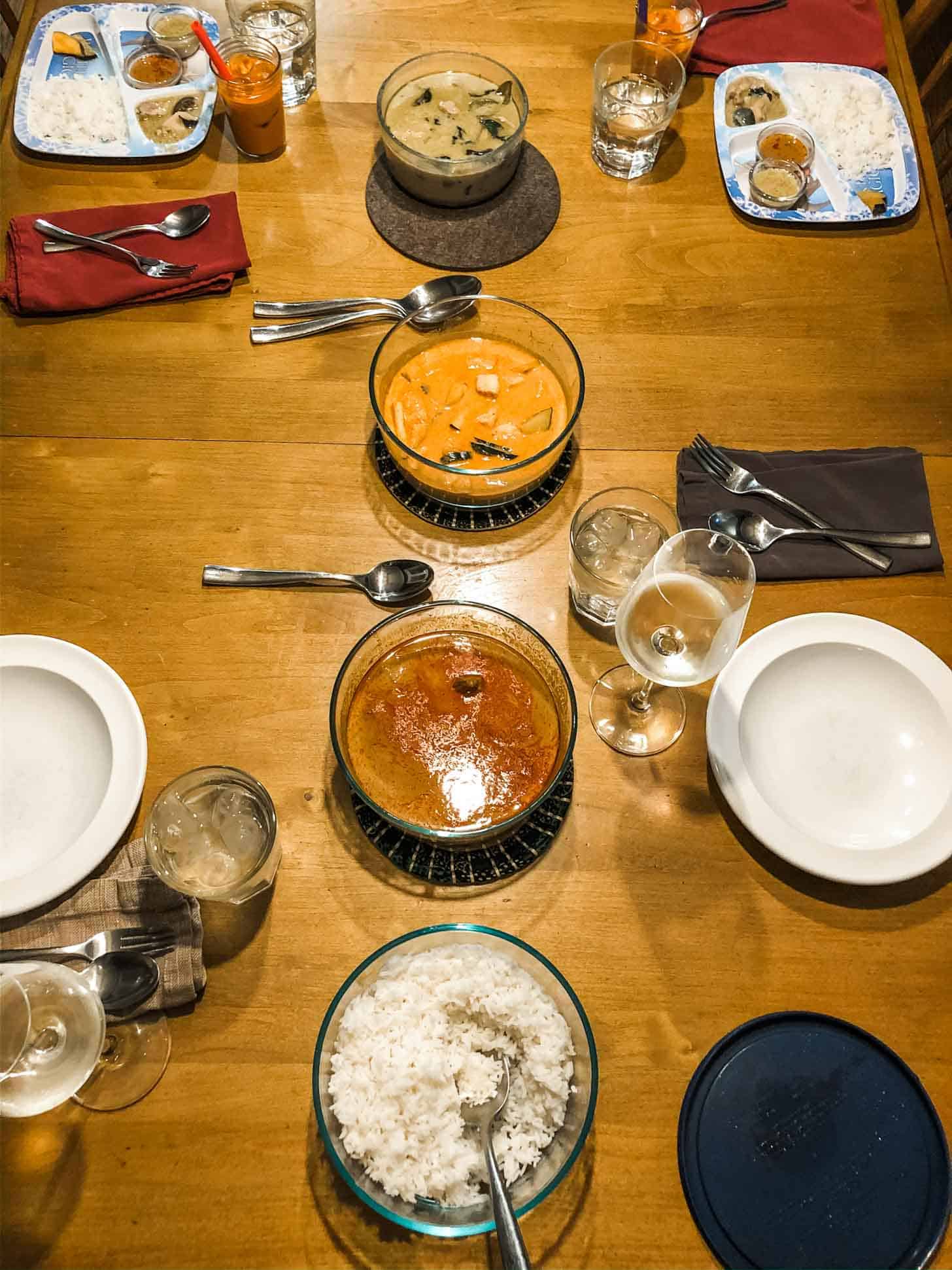 3 bowls of thai curries and rice on a table