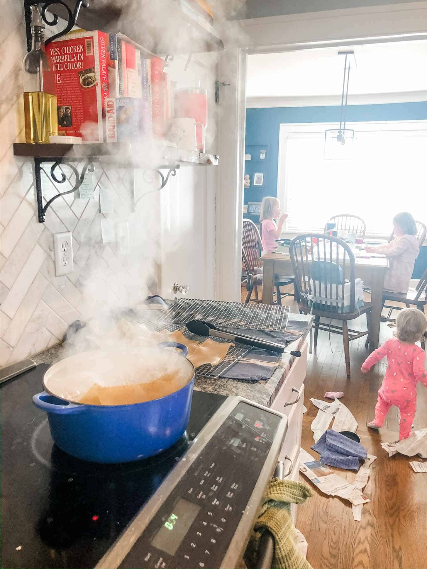 dinner cooking on the stove in a blue dutch oven with little girls playing in the background