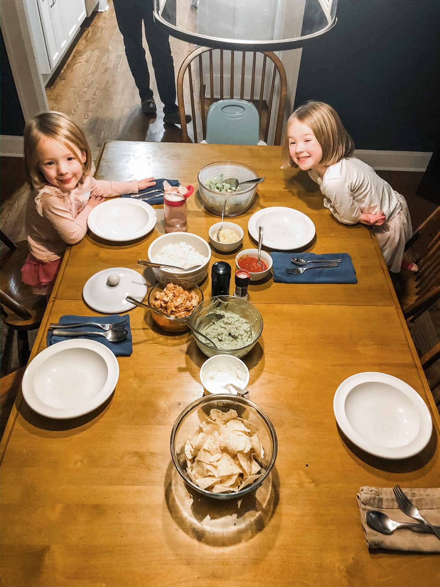 2 little girls at a table with burrito ingredients