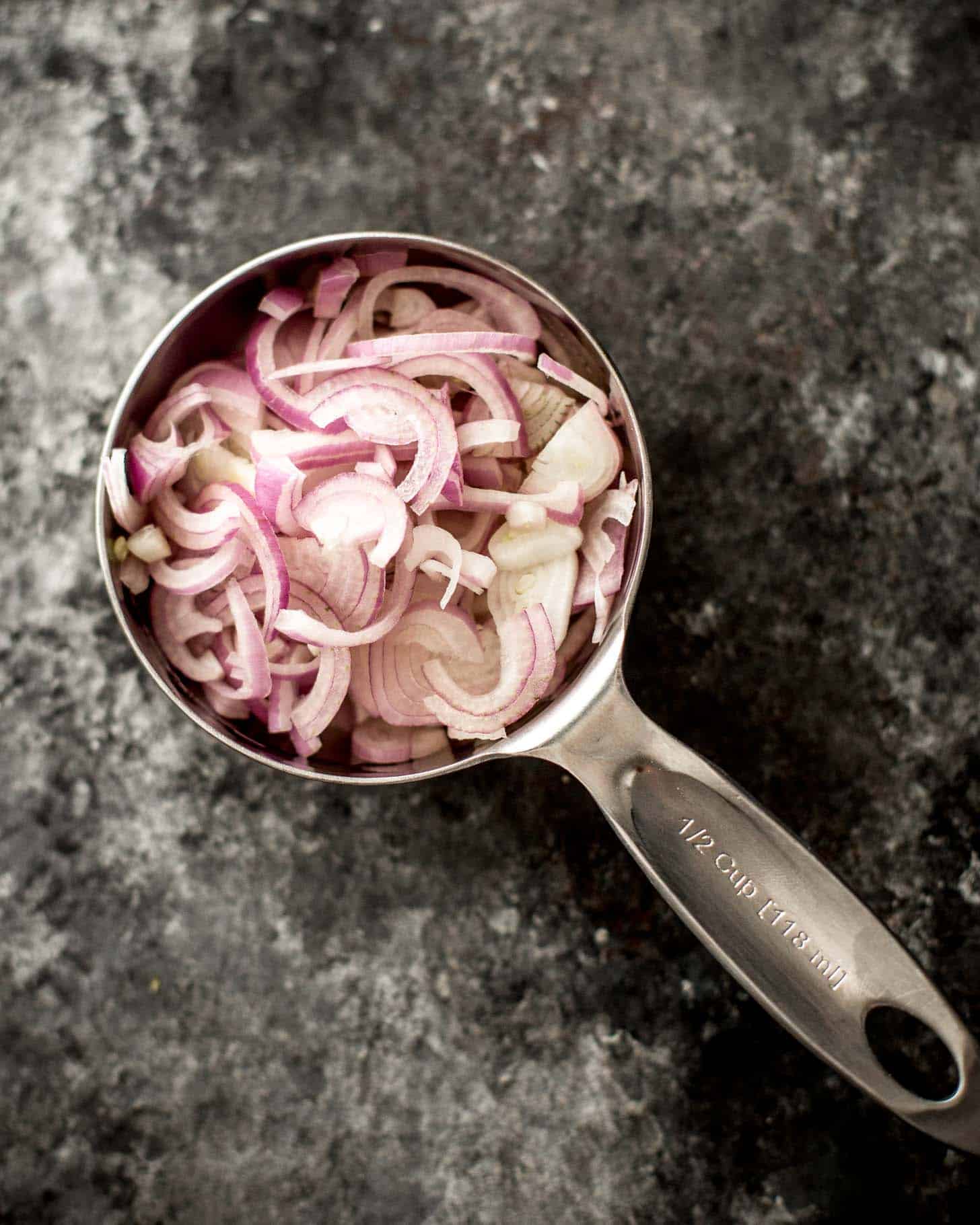 overhead image of sliced shallots in a measuring cup