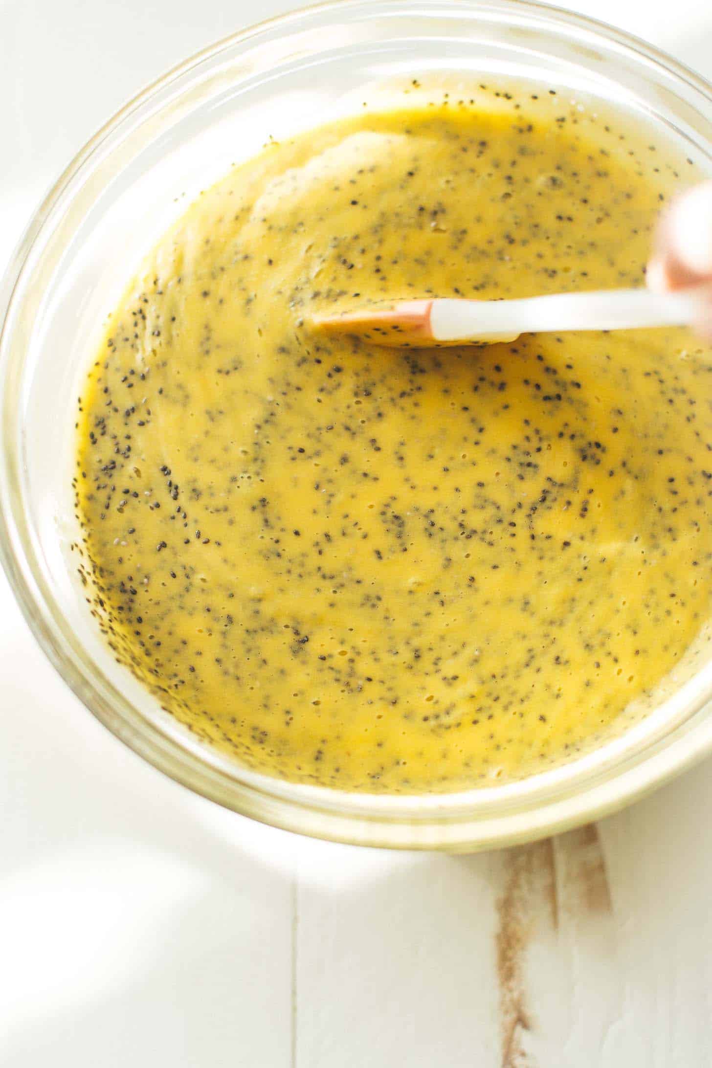 stirring mango chia seed pudding in a glass bowl