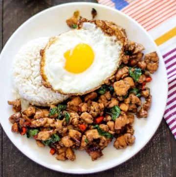 Thai Basil Chicken on a white plate with rice and a fried egg