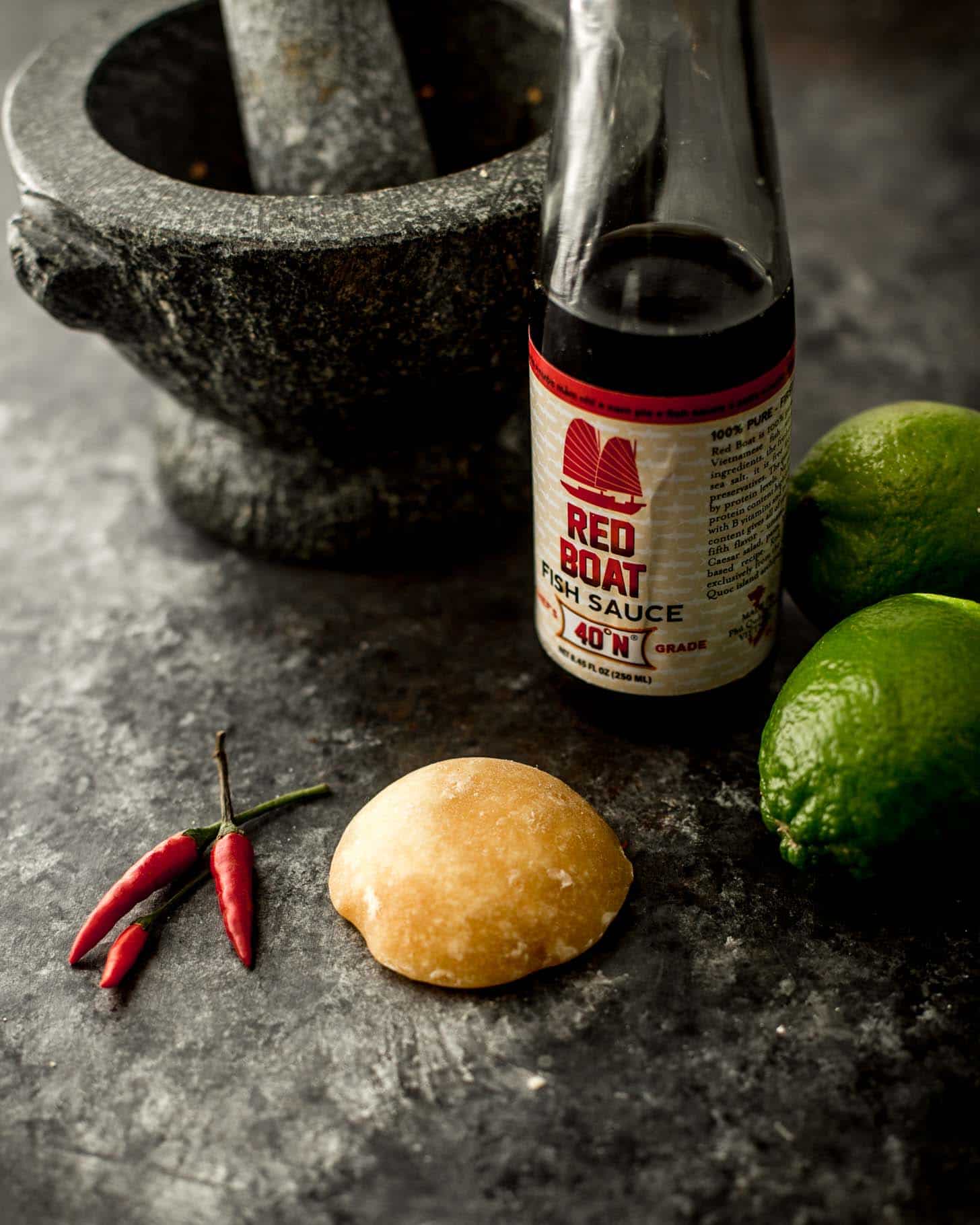 cane sugar, fish sauce, red peppers, limes on a grey countertop