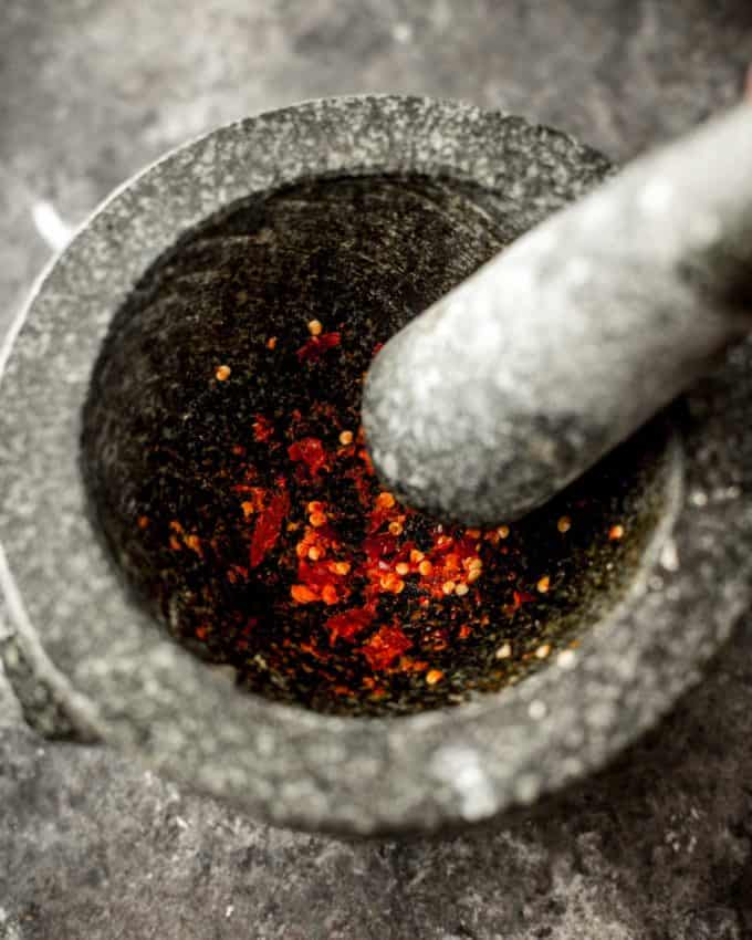 grinding bird's eye chilis with a mortar and pestle