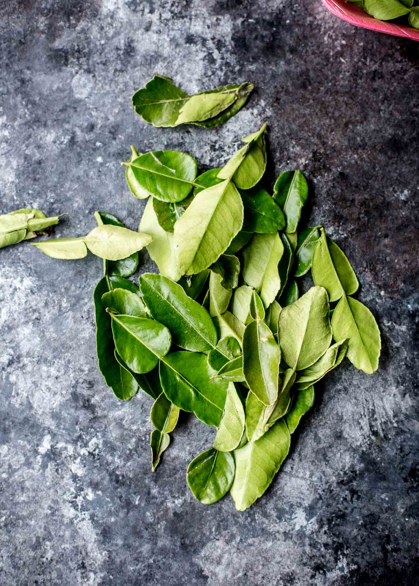 overhead image of kaffir lime leaves on a grey countertop