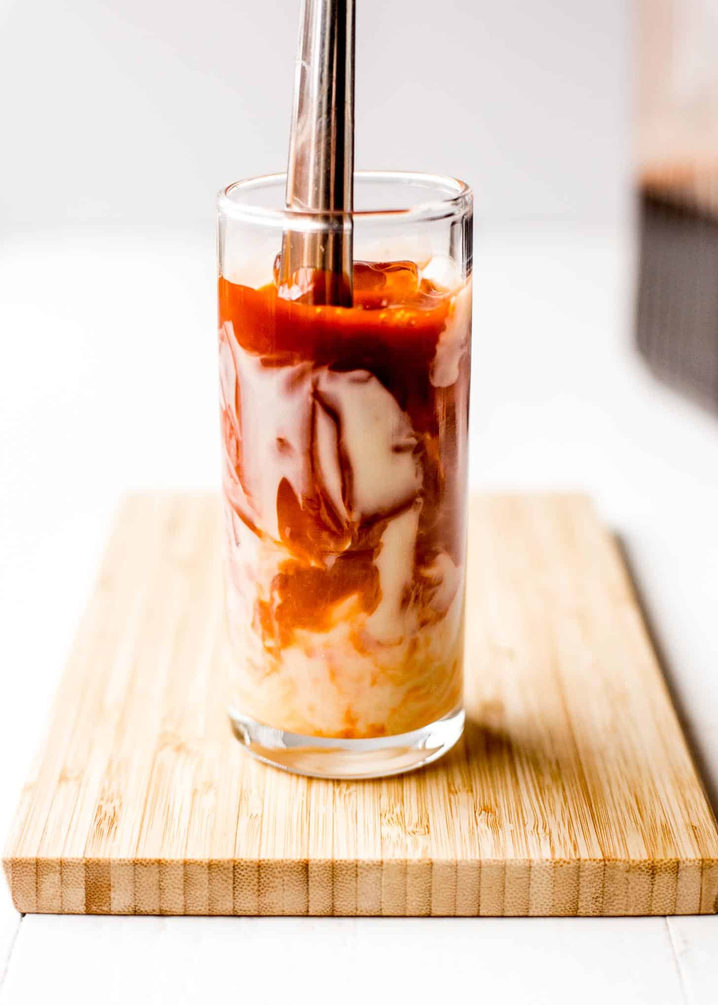 mixing milk into thai iced tea in a glass