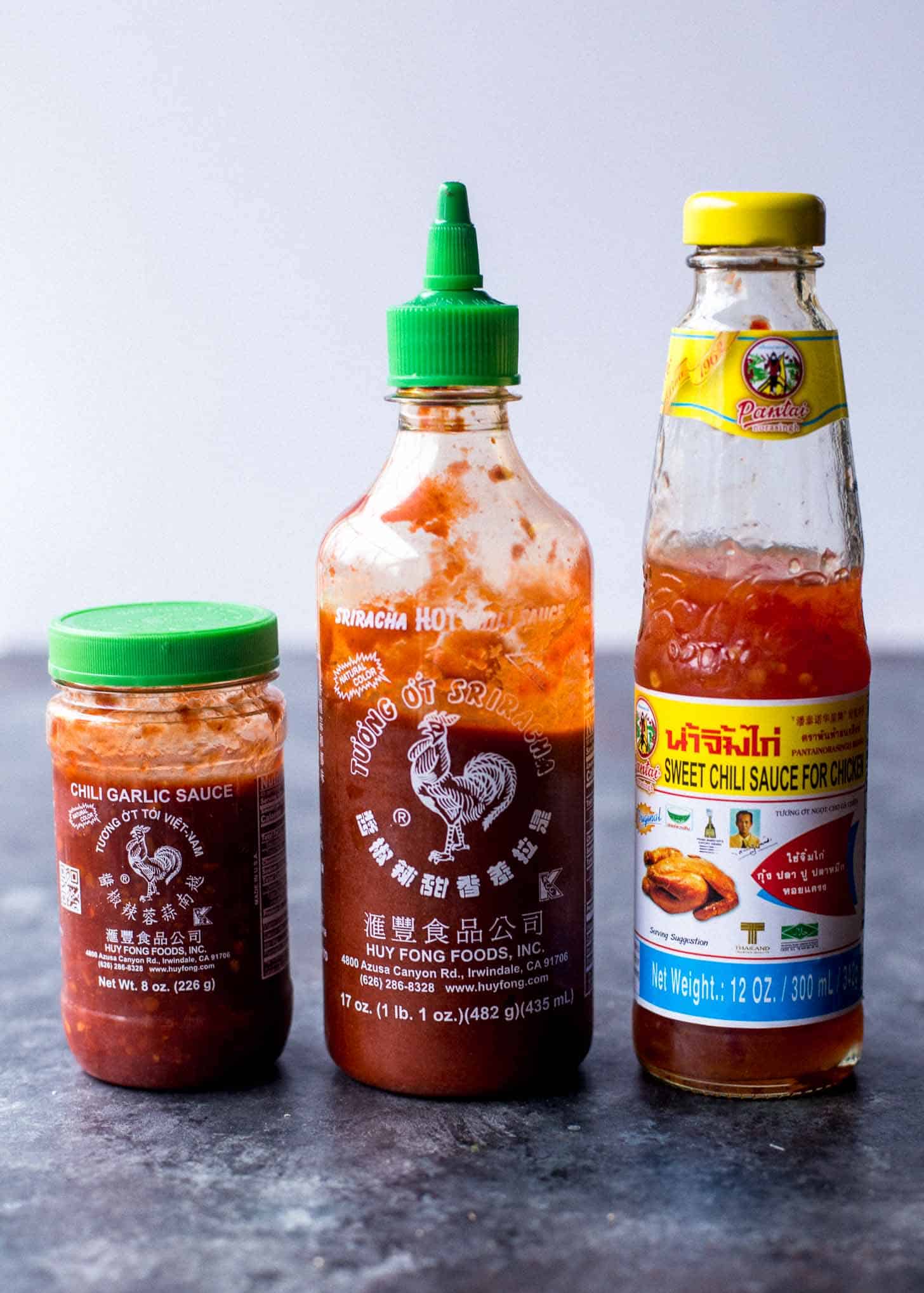 Bottles of Thai hot sauce on a grey countertop