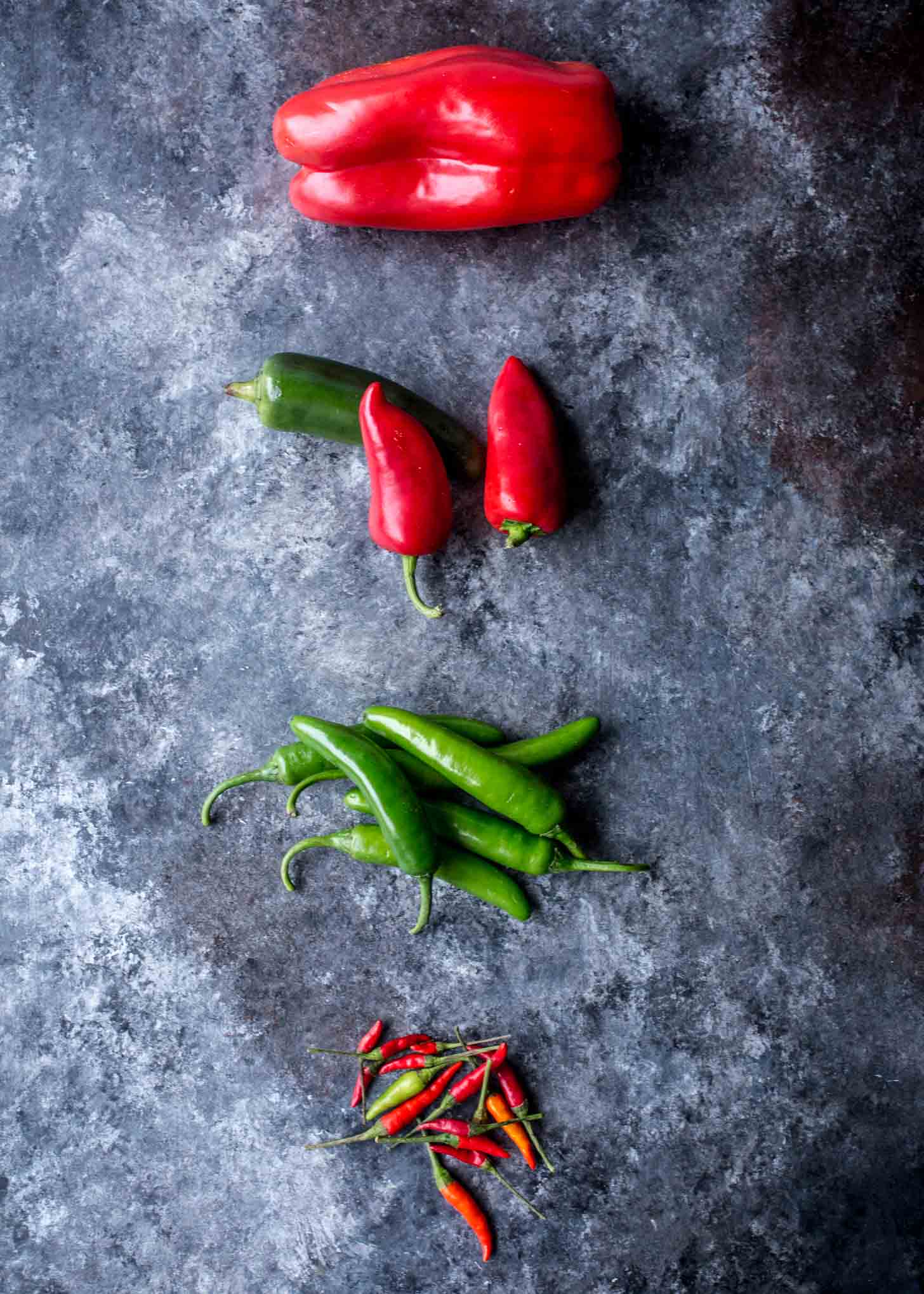 overhead image of fresh chilis on a grey countertop