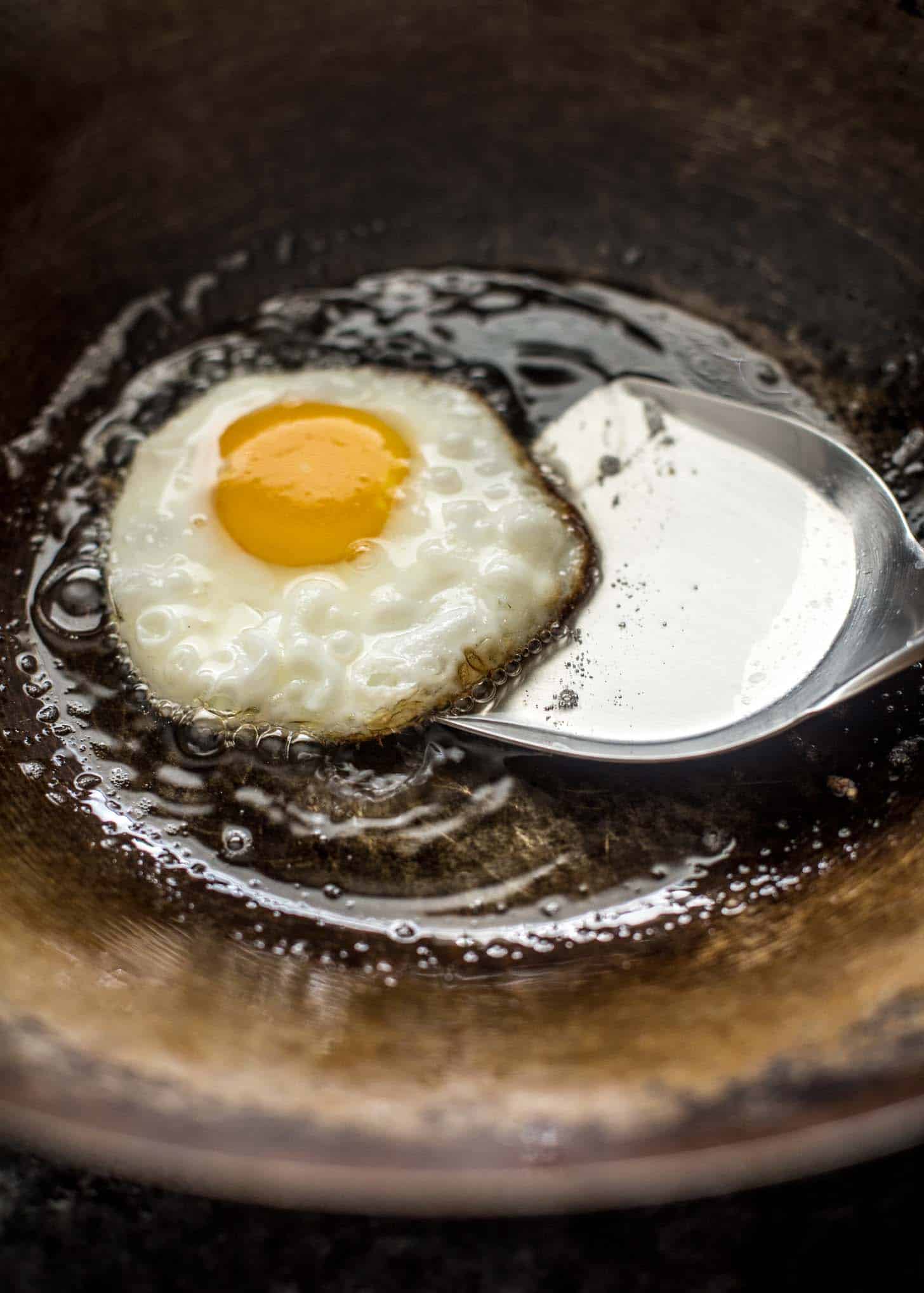 overhead image of spatula lifting a wok fried egg