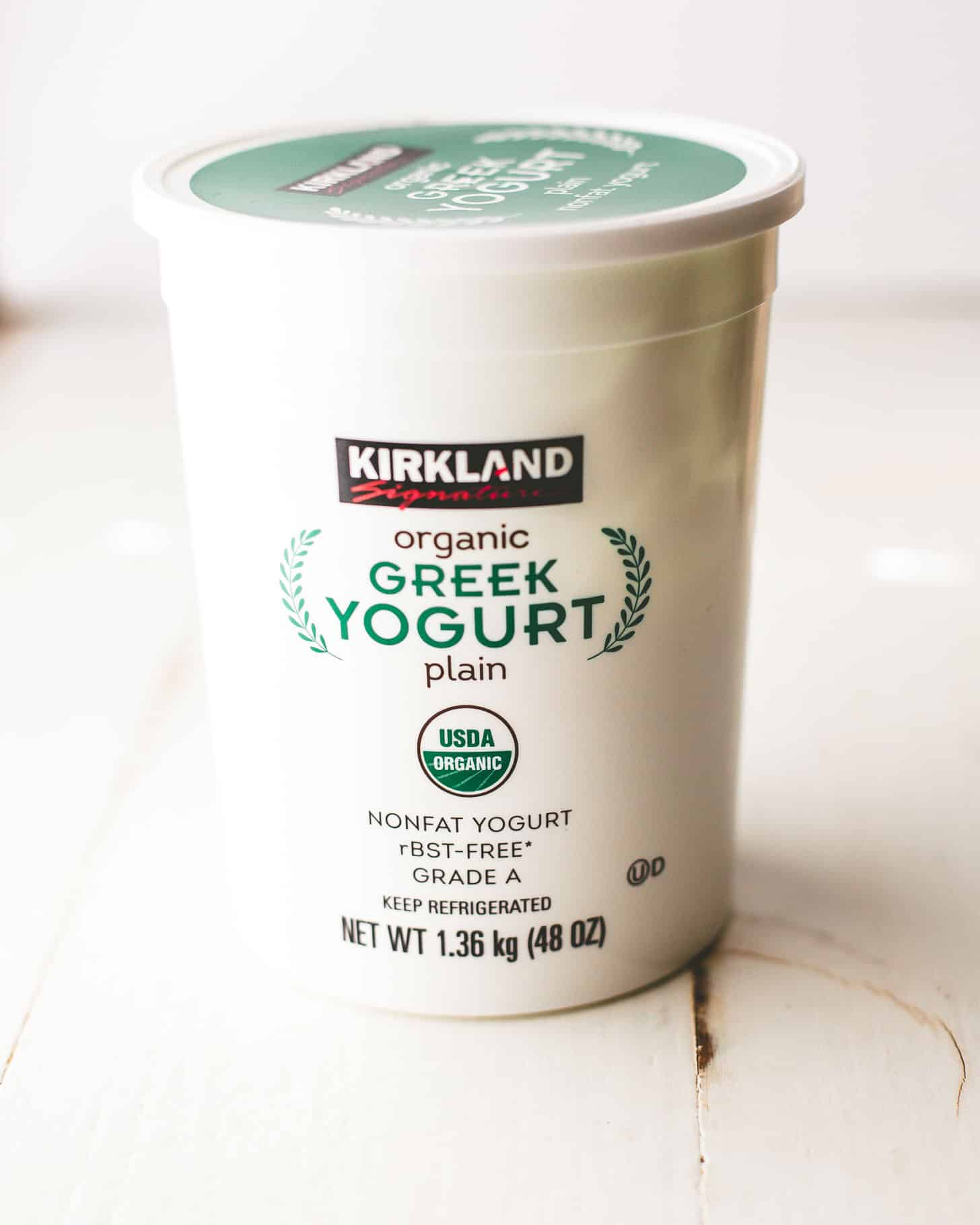 a container of greek yogurt on a white table