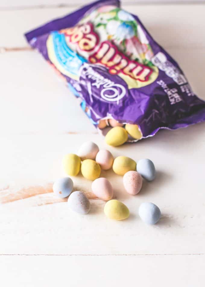 Cadbury mini eggs spilling out of a bag on a white table