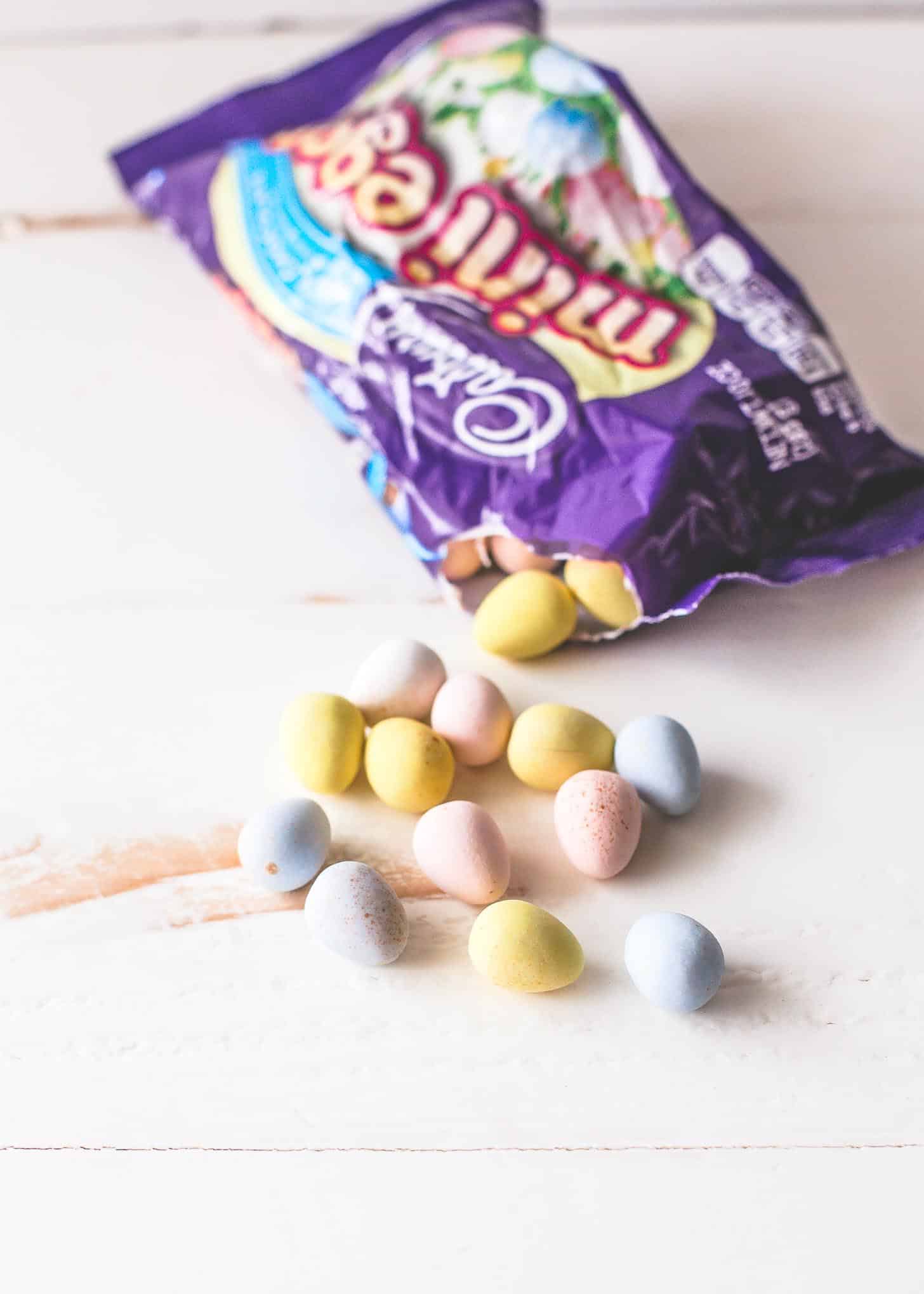 overhead image of Cadbury mini eggs spilling out of a bag on a white table