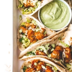 cauliflower tacos and avocado crema on a white tray