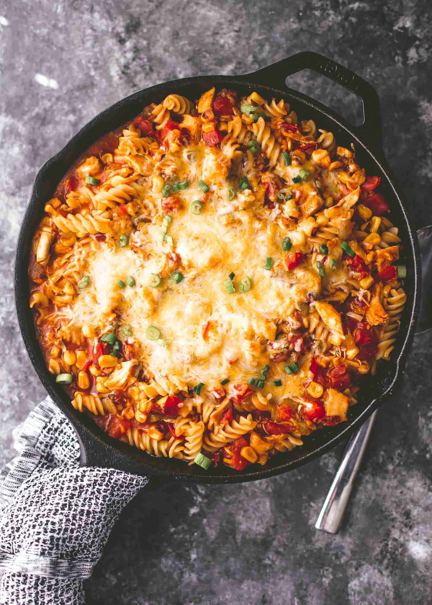 overhead image of chicken enchilada pasta in a skillet on a grey countertop