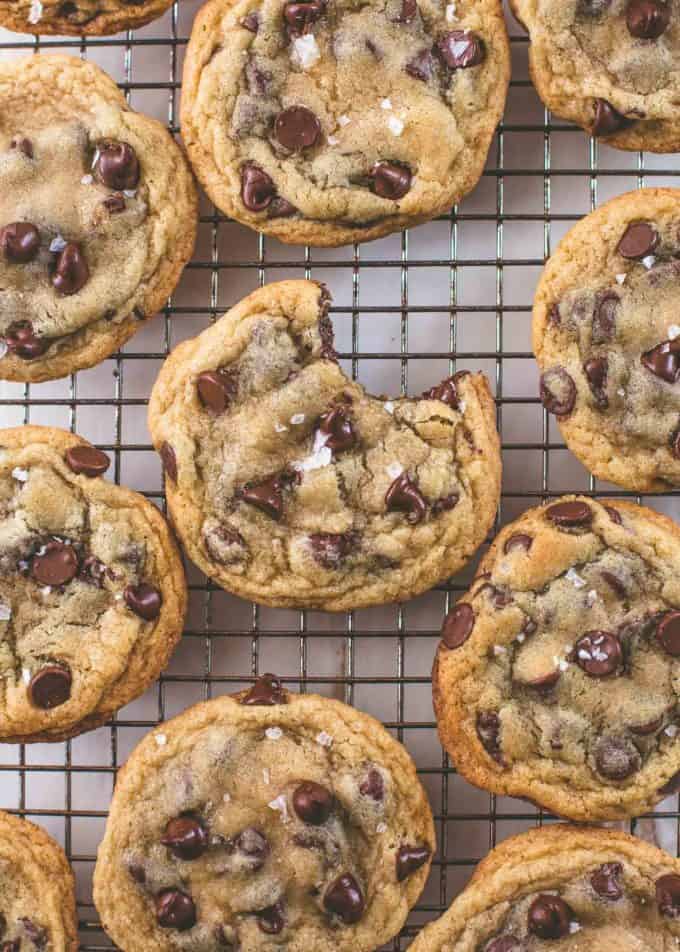 chocolate chip cookies on a cooling rack, one with a bite taken out of it