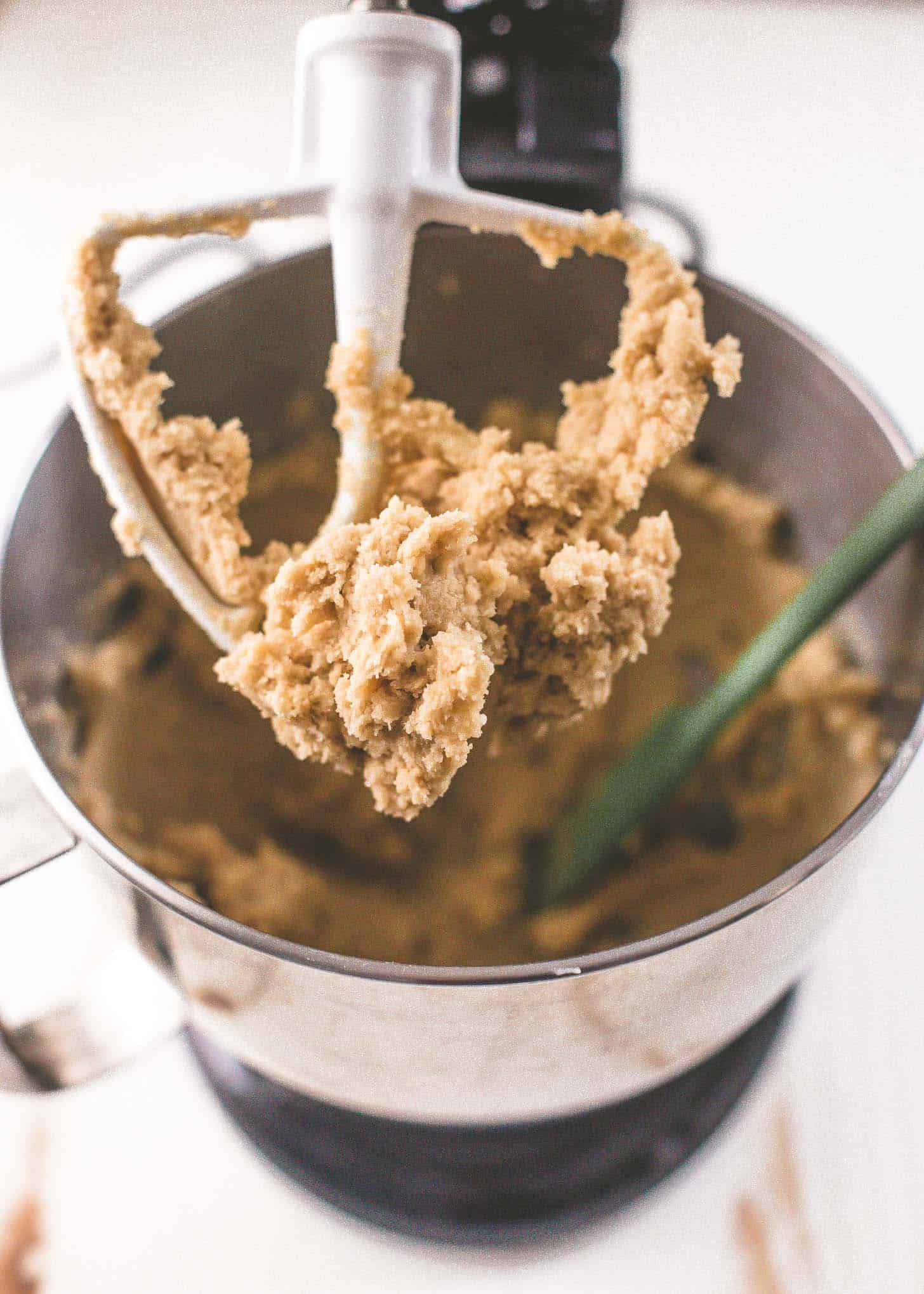 chocolate chip cookie dough on a beater above a mixer. 