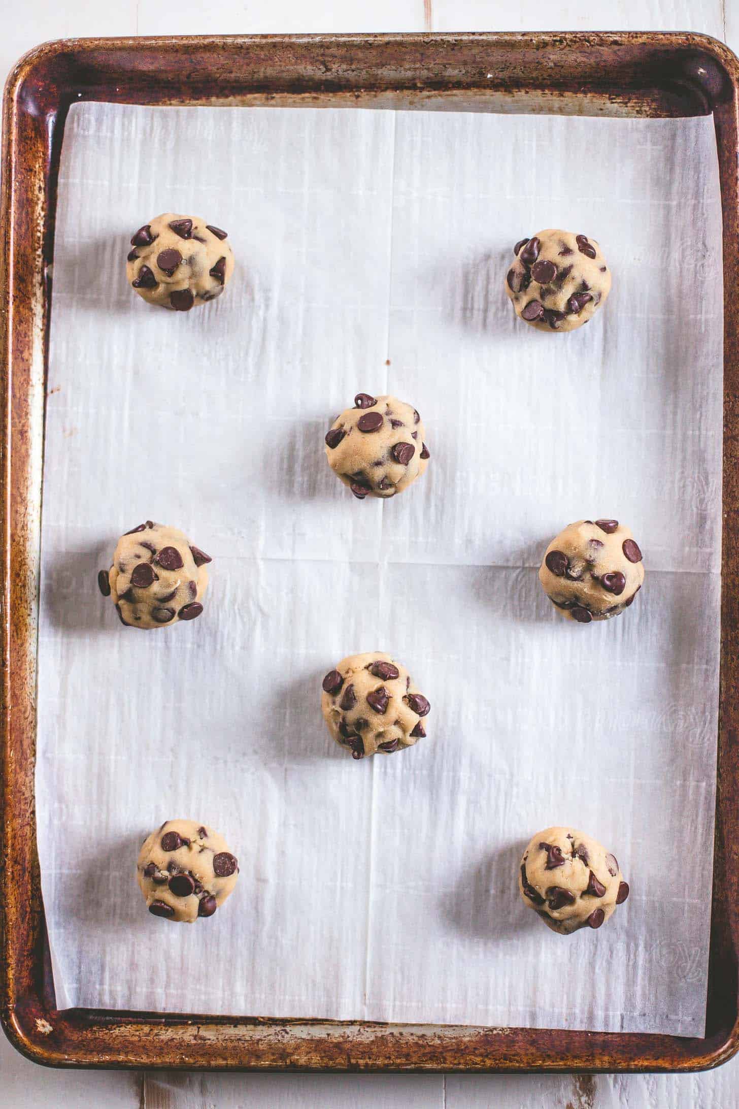 chocolate chip cookie dough in balls on a parchment lined cookie sheet