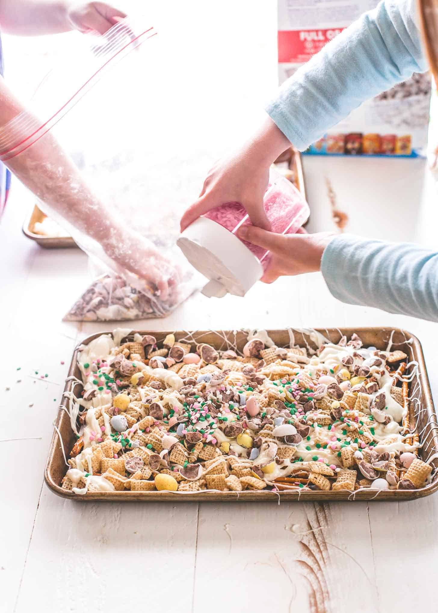 putting toppings on Easter Egg Crunch Bark on a sheet pan
