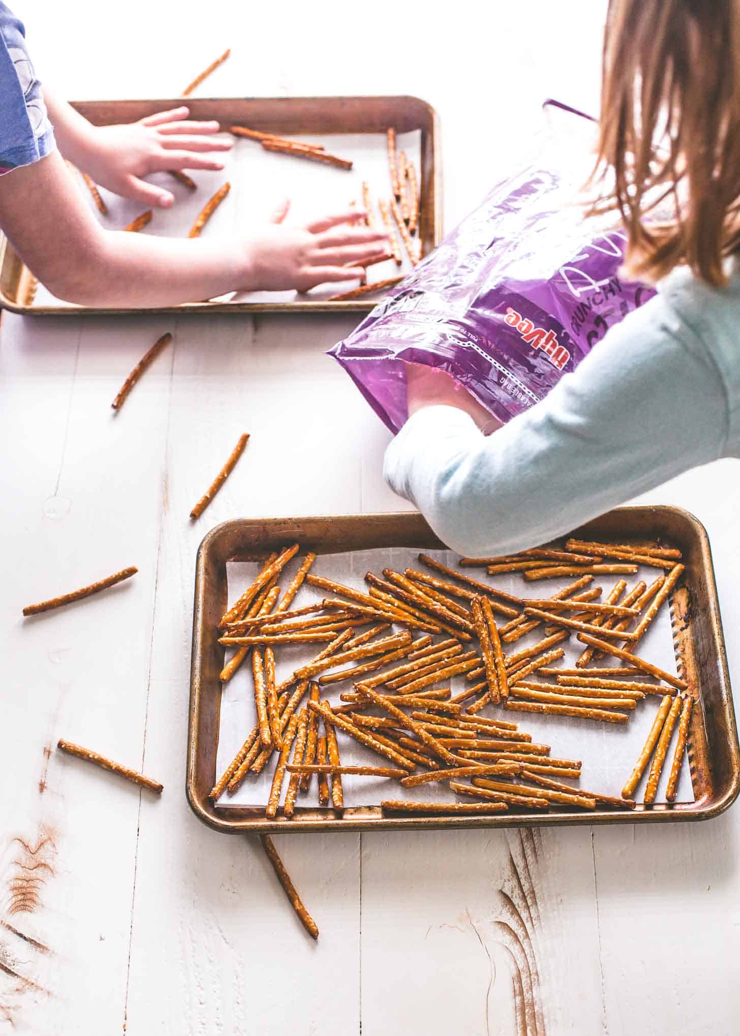 2 young girls spread Pretzels onto parchment lined sheet pans