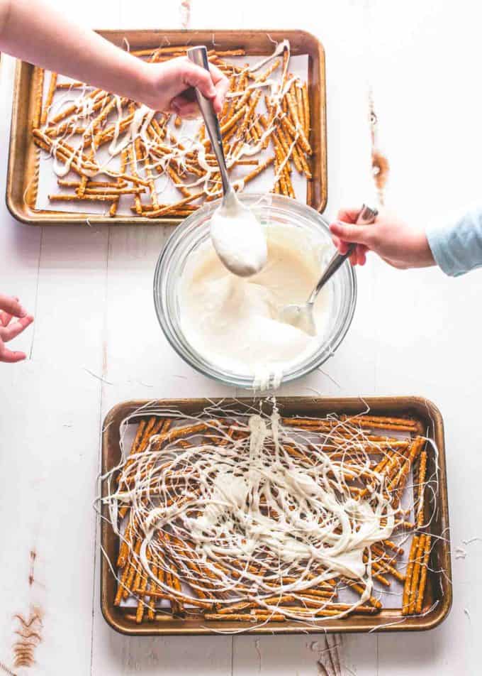 drizzling Yogurt on pretzels on parchment lined sheet pans