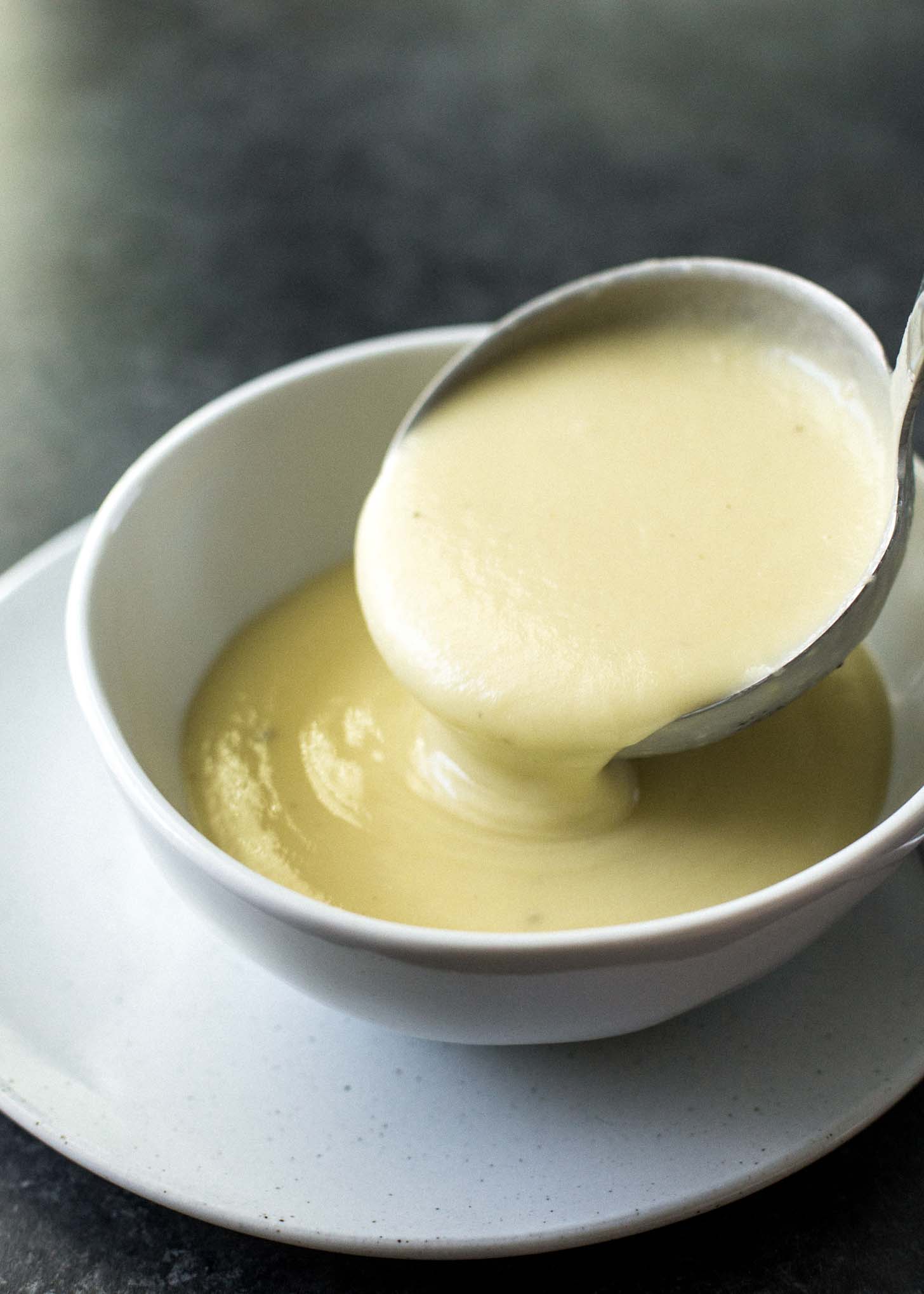ladling potato leek soup into a white bowl