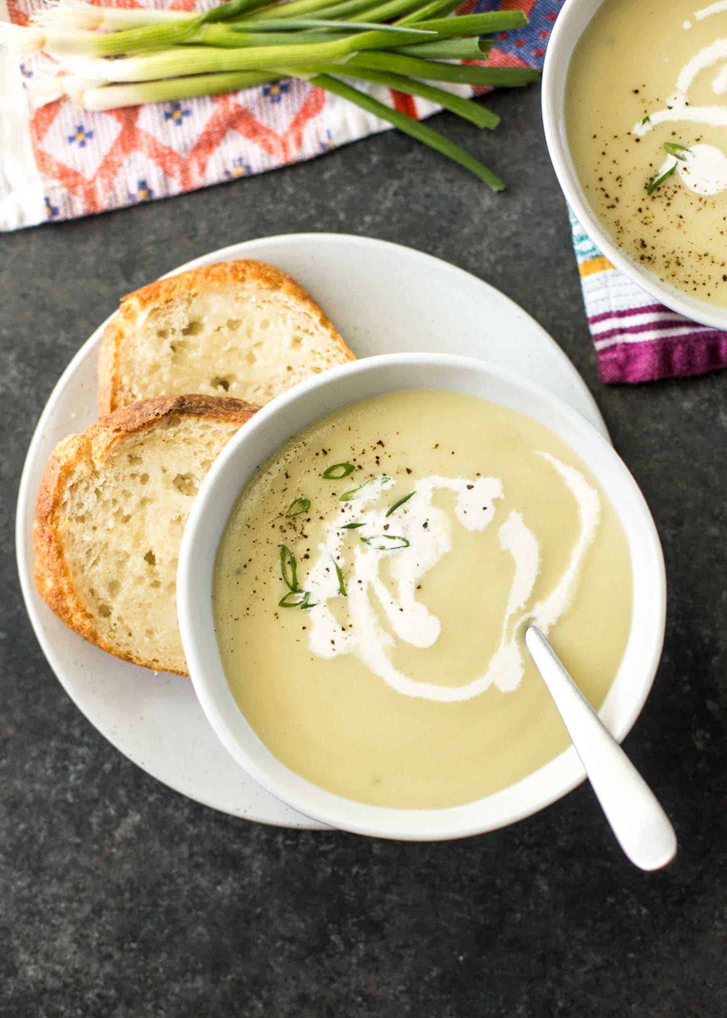 Instant Pot Potato Leek Soup in a white bowl, next to crusty bread