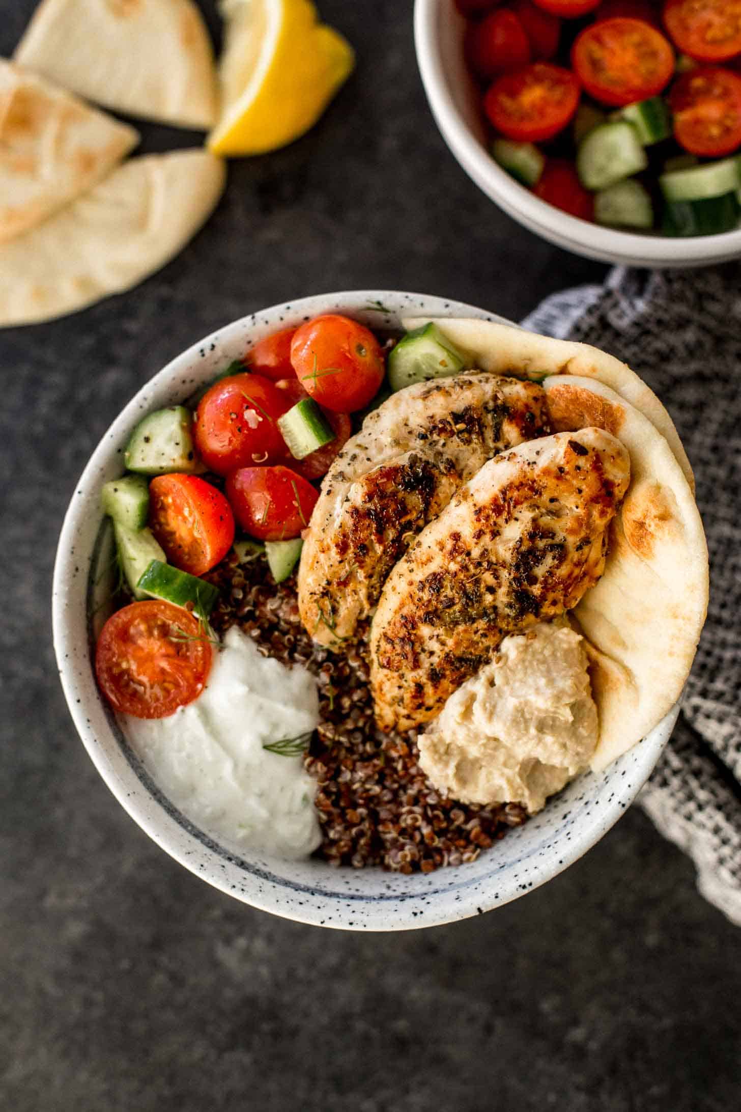 overhead image of mediterranean chicken quinoa bowl on a black countertop