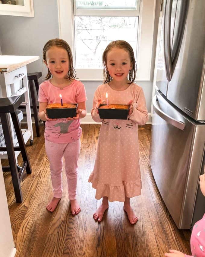 molly and clara, in pajamas, each holding a small cake with a candle 